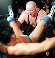 Vader powerbombs Akiyama outside the ring from Nikkan Sports